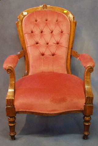 A Victorian carved walnutwood open arm chair upholstered pink buttoned material