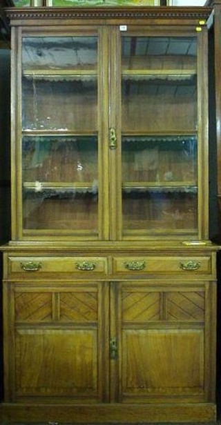 A Victorian walnutwood bookcase on cabinet with moulded cornice and dentil cornice, the interior fitted adjustable shelves enclosed by glazed panelled doors, the base fitted 2 drawers above a double cupboard, raised on a platform base 43"