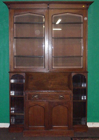 A handsome Arts & Crafts period mahogany bureau bookcase, the upper section with moulded cornice, fitted adjustable shelves enclosed by arched bevelled plate panelled doors, the fall front revealing a well fitted interior above 1 long drawer and a double cupboard flanked by a pair of bookcases 56"