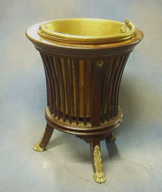 An Edwardian circular slatted mahogany planter complete with brass liner and swing handle, raised on outswept supports with metal paw mounts 15"