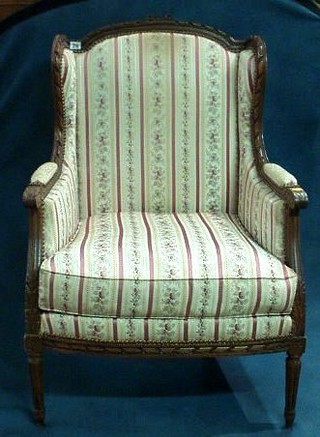 A French carved walnutwood show frame armchair on turned and reeded supports and a matching crescent shaped stool