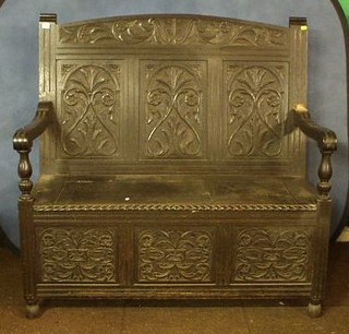 A Victorian carved oak settle with raised back and hinged seat 63"