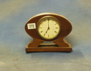 A 1930's 8 day bedroom timepiece contained in an oval inlaid mahogany case