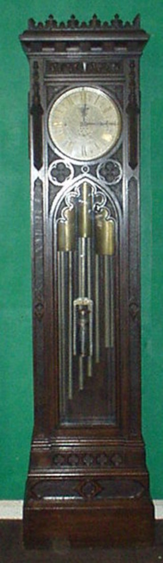 A fine and handsome Victorian Gothic 8 day quarter chiming longcase clock by Pearce & Sons of Leeds, the 12" circular silvered dial with floral and foliate engraving and Roman numerals, having a minute indicator, strike/chime silent indicator, regulation for Whittington/Westminster chimes, the clock chimes on 8 tubular bells with 8 hammers from a transverse pinned barrel, with further tubular bell for the strike, the movement has 4 substantial pillars and plates which are numbered 4654 to the base, contained in a carved oak case 89"  
