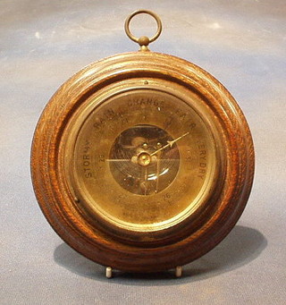 An aneroid barometer with gilt metal dial contained in a circular oak case 6"