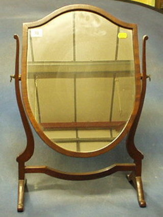 A shield shaped plate dressing table mirror contained in a mahogany swing frame
