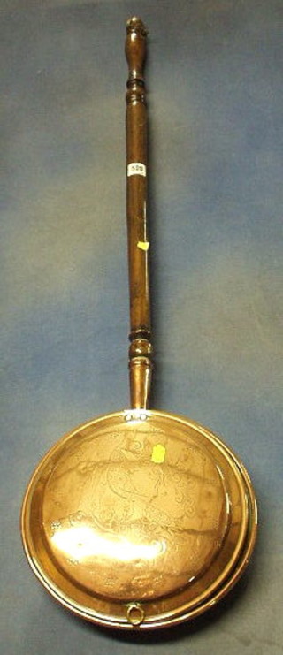 An 18th Century engraved copper warming pan with turned fruit wood handle