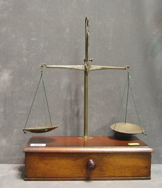 A set of brass apothecary scales raised on a mahogany base fitted a drawer