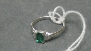 A lady's 18ct white gold dress ring set a rectangular cut emerald and supported by 4 baguette cut diamonds