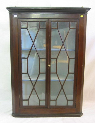 A 19th Century mahogany hanging corner cabinet with moulded cornice, the interior fitted shelves enclosed by astragal glazed doors, 32"