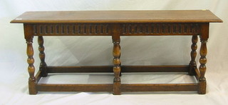 A rectangular oak bench with arcaded decoration raised on turned and block supports united by stretchers 48"