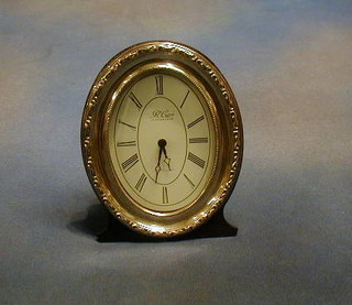 A oval battery operated mantel clock contained in a silver frame