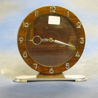 An Art Deco mantel clock contained in a walnutwood case with silvered Arabic numerals