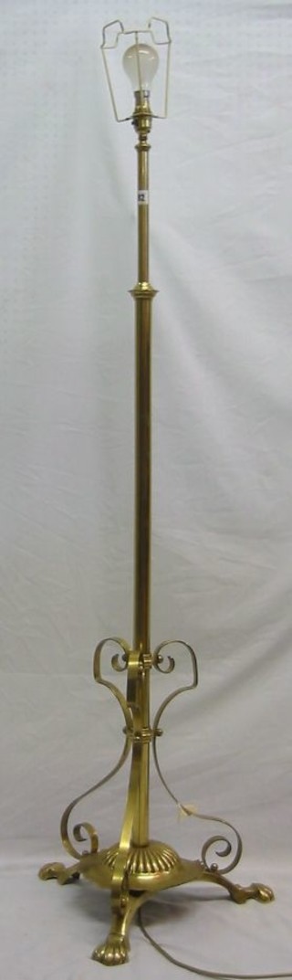 A brass adjustable standard lamp raised on 3 hoof feet