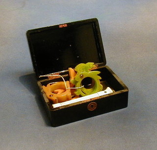 A lacquered box containing 5 Bakelite napkin rings and a torch