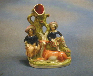 A Staffordshire spill vase in the form of a seated Scotsman and lass by a deer 8"