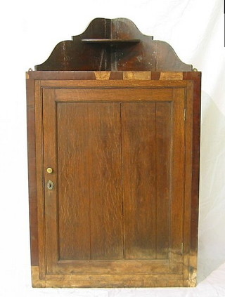 A Georgian oak hanging corner cabinet, the interior fitted shaped shelves enclosed by panelled doors 39"