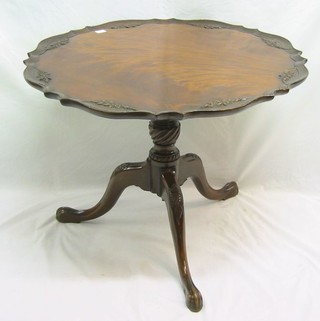 A circular Georgian mahogany tea table with bracketed border and carved decoration, raised on  a turned column and tripod supports ending in egg and claw feet 32" (reduced in height)
