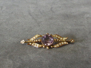 An Edwardian 9ct gold bar brooch set an oval amethyst supported by demi-pearls