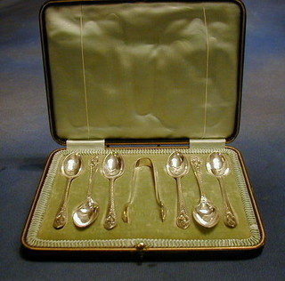 A set of 6  silver plated tea spoons with tongs contained in a fitted case, the lid decorated the arms of the Cutler's Company