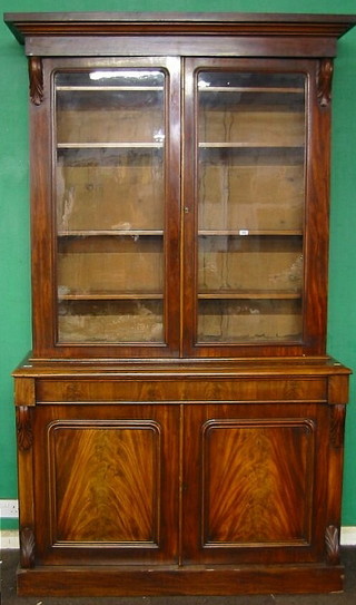 A Victorian mahogany bookcase on cabinet with moulded cornice, the upper section fitted adjustable shelves enclosed by glazed panelled doors, the base fitted 1 long drawer above a double cupboard raised on a platform base 54"