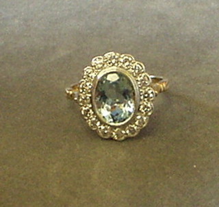 A lady's gold dress ring set an oval cut aquamarine surrounded by 16 diamonds