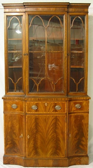 A Georgian style inlaid mahogany breakfront bookcase, the upper section with moulded cornice fitted a cupboard flanked by a pair of cupboards enclosed by glazed panelled doors, the base fitted 1 long drawer above a cupboard flanked by a pair of concave cupboards 40"