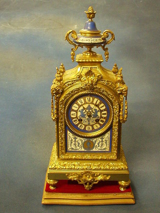 A French 19th Century 8 day striking mantel clock with porcelain panels contained in a gilt "Ormolu" case, surmounted by a lidded urn 17"