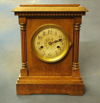 A 19th Century German 8 day striking mantel clock with silvered dial contained in an oak case supported by turned and reeded columns