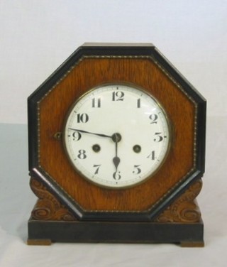 A 1920's striking mantel clock with enamelled dial and Arabic numerals contained in an oak octagonal case