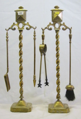 A pair of brass fireside companion sets raised on spiral turned columns