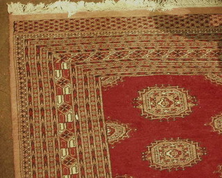 A contemporary red ground Bokhara carpet with 3 octagons to the centre within multi row borders, 95" x 63"