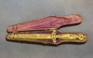 A 19th Century steel bladed dagger, contained in a brass scabbard, the handle decorated Roman armour, in a fitted leather case