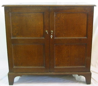 A Georgian oak linen cabinet with hinged lid, the interior fitted shelves enclosed by panelled doors with ivory escutcheon, raised on bracket feet 54"