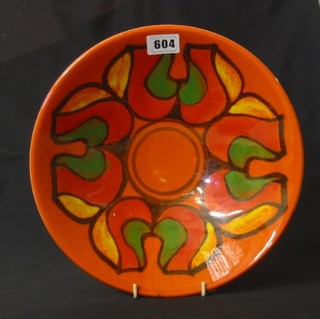 A circular burnt orange Poole Pottery dish, the base marked England 57 R 10 1/2"