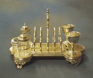A silver plated egg cruet incorporating a 2 egg cups, a 5 bar toast rack and 3 piece condiment set, raised on pierced panelled supports