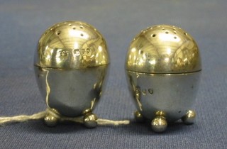 A pair of Victorian oval circular silver pepperettes raised on bun feet, London 1893