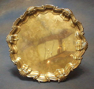 A circular silver plated salver with bracketed border, raised on 3 ball and claw supports 10"