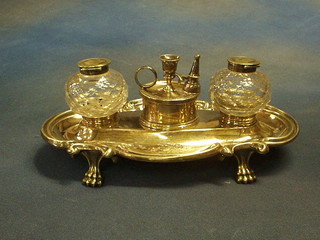 A handsome Edwardian silver plated standish with circular trinket box to the centre, surmounted by a chamber stick, flanked by a pair of cut glass inkwells (1 with chip to base) and with pen receptical to either side, raised on panel supports 9"