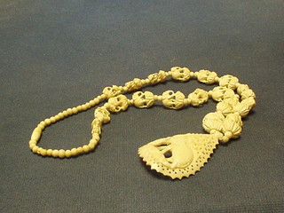 A pierced ivory pendant decorated an elephant hung on a string of ivory beads