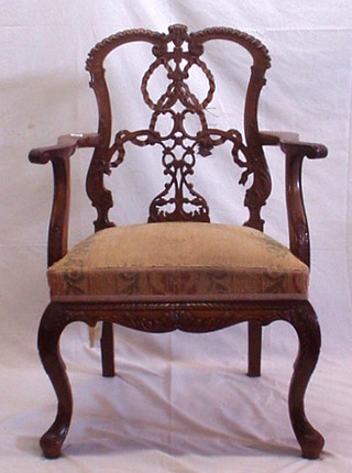 A carved walnutwood Chippendale style open arm carver chair with pierced vase splat back and upholstered seat, on carved cabriole supports