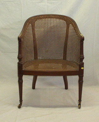 A William IV mahogany framed library chair with woven cane seat and back, on turned supports ending in brass caps and castors