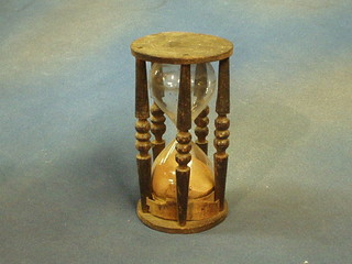 An hour glass contained in a turned oak stand