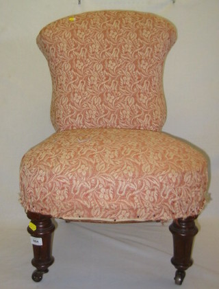 A Victorian walnutwood nursing chair, upholstered pink sculpted material, on turned and fluted supports