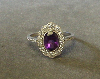A lady's white gold dress ring set an oval cut amethyst surrounded by 14 diamonds and with 8 diamonds to the shoulders