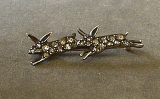 A lady's diamond set brooch in the form of 2 running rabbits, the eyes set rubies