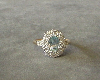 A lady's gold dress ring set an oval cut aquamarine surrounded by 11 diamonds and with 2 diamonds to the shoulders