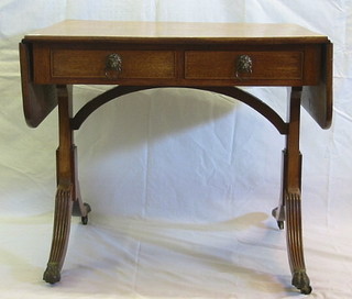 A 19th Century mahogany sofa table fitted 2 drawers, raised on standard end supports with sabre legs, ending in brass paw feet 33"
