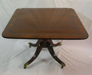 A Georgian mahogany rectangular breakfast table with crossbanded top, raised on a gun barrel turned column with tripod supports ending in brass caps and castors 42"