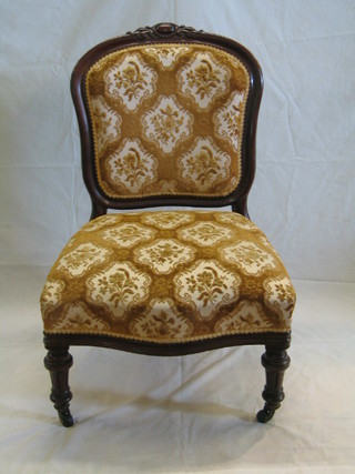 A  Victorian mahogany show frame nursing chair with carved cresting rail and upholstered seat, on turned supports